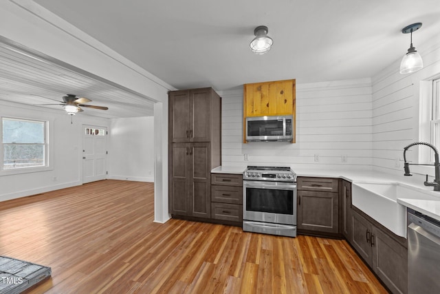 kitchen with sink, ceiling fan, appliances with stainless steel finishes, hanging light fixtures, and light wood-type flooring