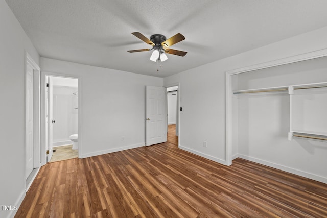 unfurnished bedroom with ceiling fan, dark hardwood / wood-style floors, connected bathroom, a textured ceiling, and a closet