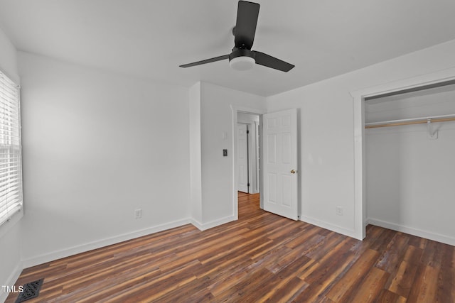 unfurnished bedroom featuring multiple windows, dark hardwood / wood-style floors, ceiling fan, and a closet