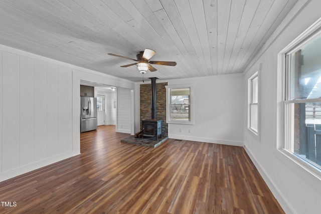 unfurnished living room featuring ceiling fan, a wood stove, wood ceiling, and dark hardwood / wood-style floors