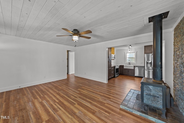 unfurnished living room with sink, wood ceiling, wood-type flooring, a wood stove, and ceiling fan