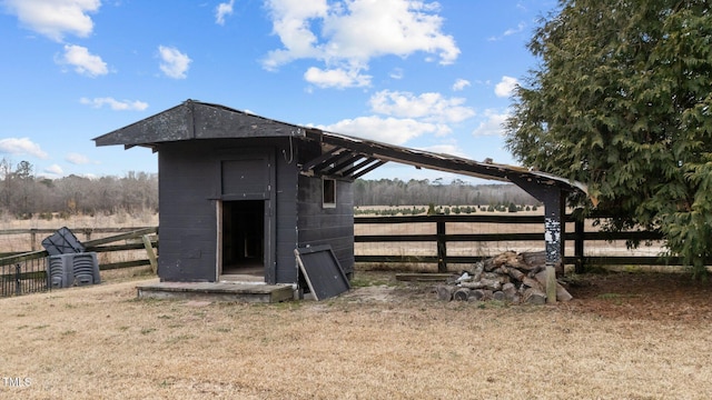 view of outdoor structure featuring a rural view and a lawn