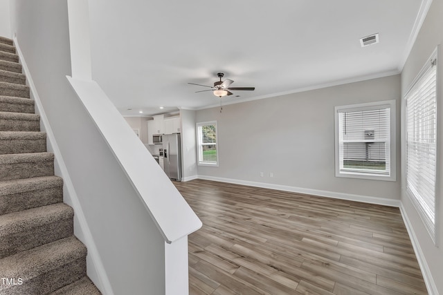 stairs with hardwood / wood-style floors, ornamental molding, and ceiling fan