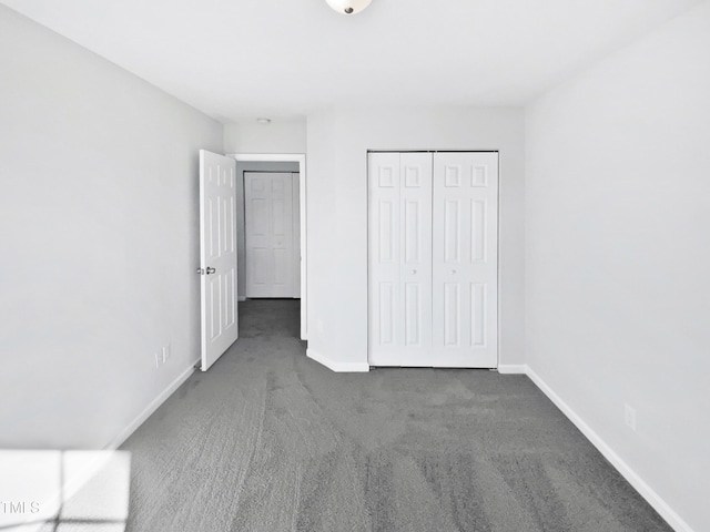 unfurnished bedroom with dark carpet and a closet