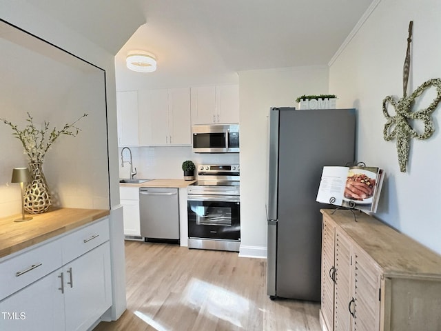 kitchen with sink, light hardwood / wood-style flooring, backsplash, stainless steel appliances, and white cabinets