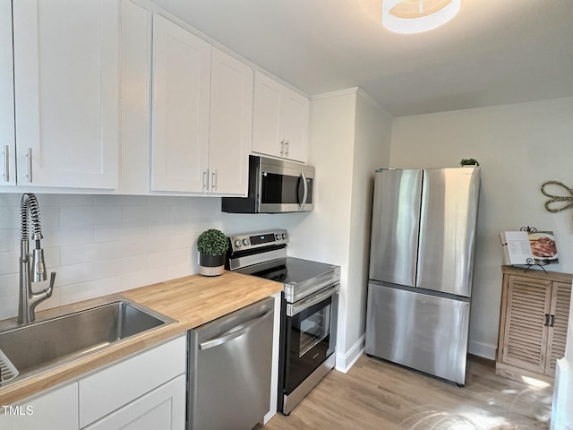 kitchen with stainless steel appliances, sink, white cabinets, and decorative backsplash