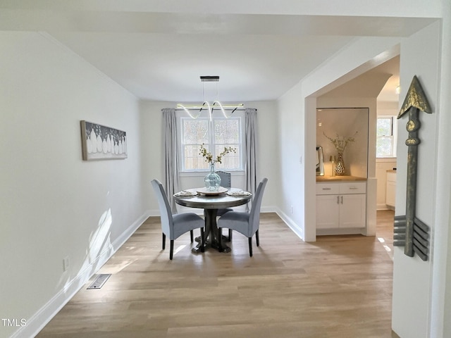 dining area with a notable chandelier, light hardwood / wood-style floors, and a wealth of natural light