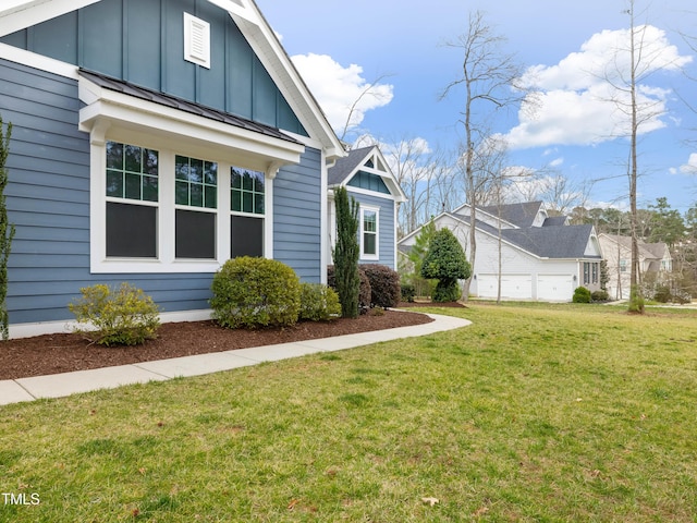 view of side of property with a standing seam roof, a lawn, board and batten siding, and metal roof