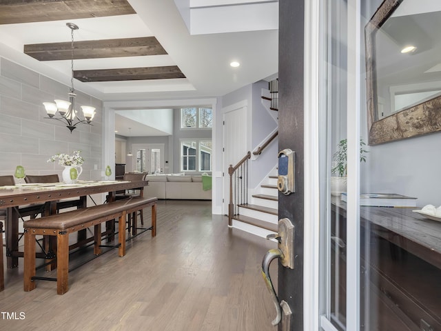 entryway featuring a notable chandelier, a tray ceiling, wood finished floors, recessed lighting, and stairs