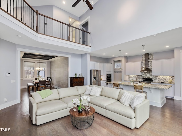 living area with a high ceiling, wood finished floors, baseboards, and ceiling fan