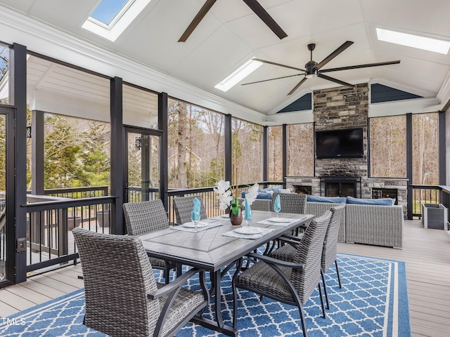 sunroom / solarium with a healthy amount of sunlight, a fireplace, ceiling fan, and vaulted ceiling