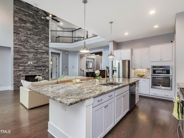 kitchen featuring a sink, appliances with stainless steel finishes, dark wood-style flooring, and a fireplace