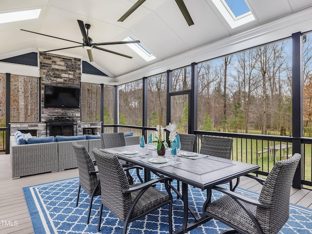 sunroom featuring an outdoor stone fireplace, a ceiling fan, and vaulted ceiling