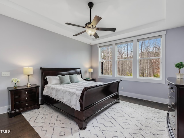 bedroom featuring a tray ceiling, multiple windows, and wood finished floors