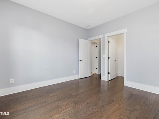 unfurnished room featuring baseboards and dark wood finished floors