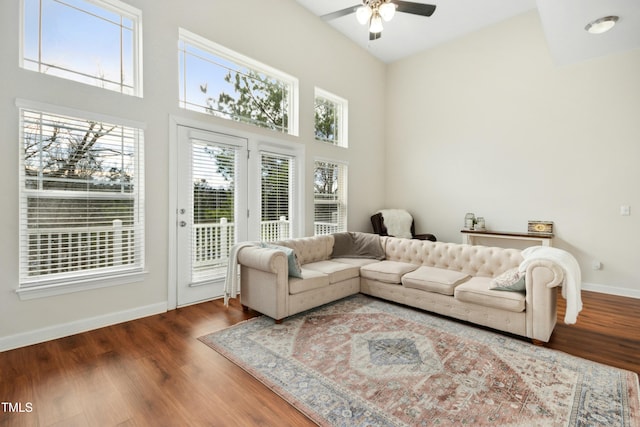 living room with hardwood / wood-style flooring, a towering ceiling, and ceiling fan