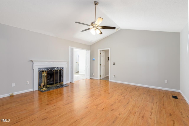 unfurnished living room featuring ceiling fan, a high end fireplace, vaulted ceiling, and light hardwood / wood-style flooring