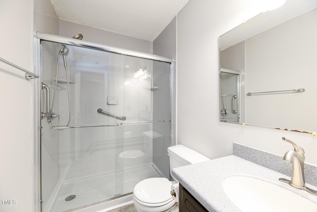 bathroom with vanity, toilet, a shower with door, and a textured ceiling