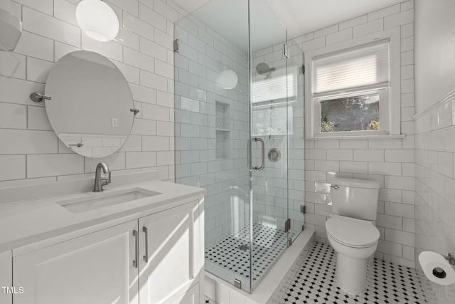 bathroom with tile patterned flooring, toilet, tile walls, and a shower with shower door