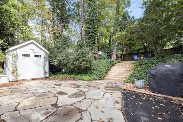 view of patio with a shed and area for grilling