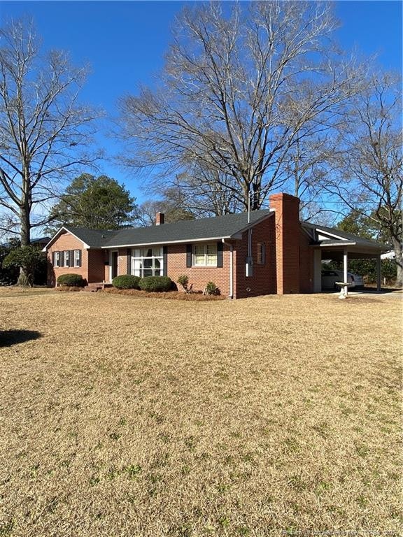 view of front of house with a carport and a front lawn