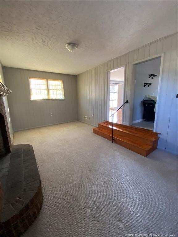 700 W 20th St W, Lumberton, NC 28358 - unfurnished living room featuring a fireplace and a textured ceiling