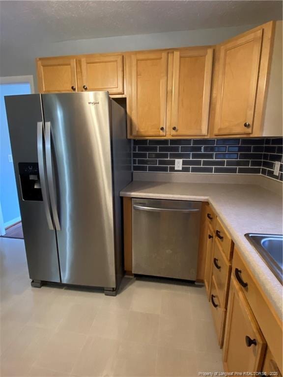700 W 20th St W, Lumberton, NC 28358 - kitchen with light brown cabinets, stainless steel appliances, light countertops, a textured ceiling, and backsplash