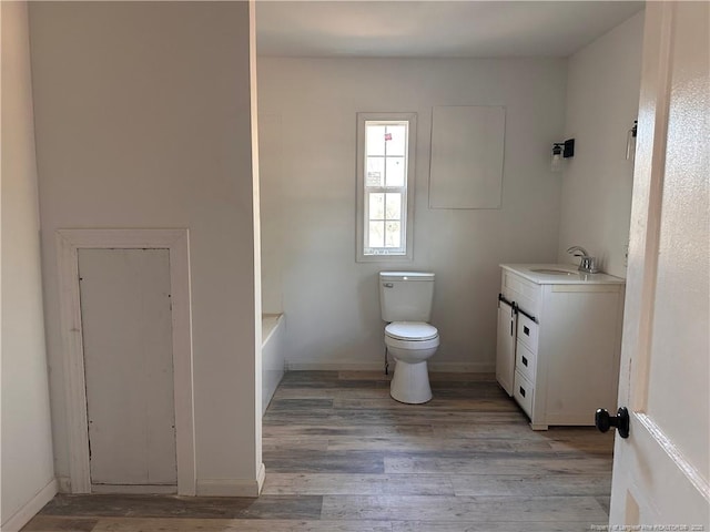 bathroom with vanity, hardwood / wood-style floors, a washtub, and toilet