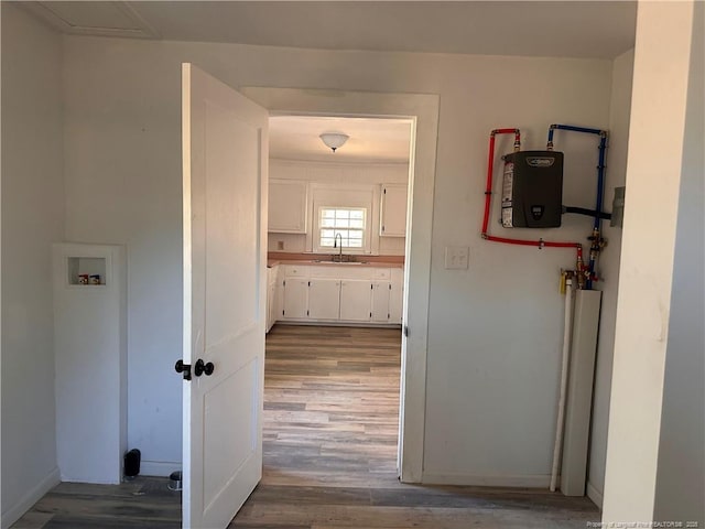 hallway with water heater, wood-type flooring, and sink