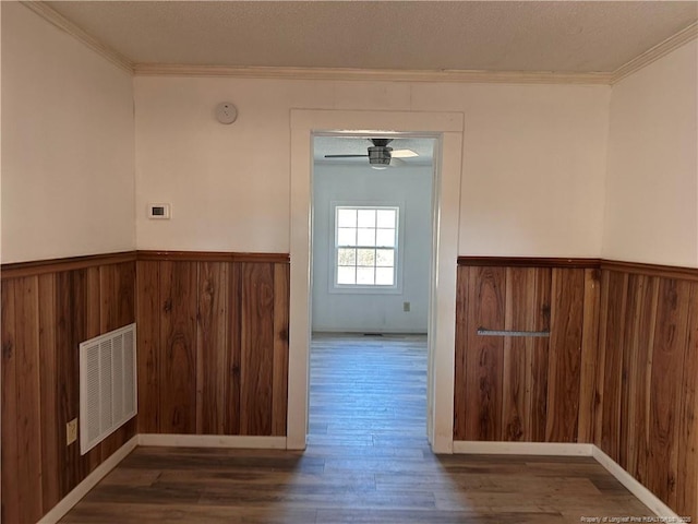 spare room with ornamental molding, dark hardwood / wood-style floors, and wood walls