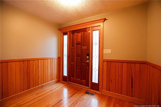 entrance foyer with hardwood / wood-style floors, a textured ceiling, and wood walls