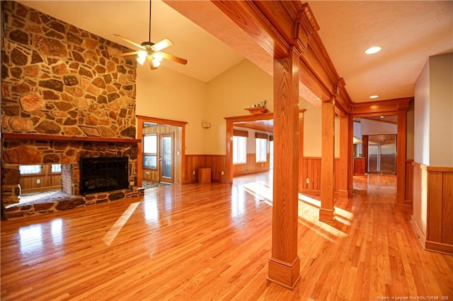 unfurnished living room featuring ceiling fan, lofted ceiling, a fireplace, and light wood-type flooring