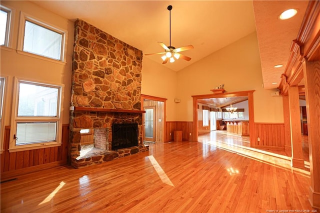 unfurnished living room with hardwood / wood-style flooring, a fireplace, high vaulted ceiling, and ceiling fan