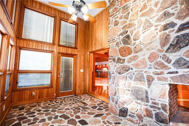 foyer with wooden walls, ceiling fan, and a high ceiling