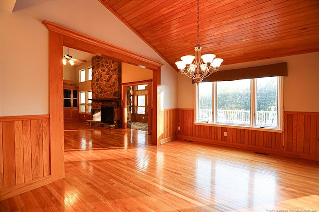 unfurnished dining area with lofted ceiling, wood ceiling, a fireplace, light hardwood / wood-style floors, and ceiling fan with notable chandelier