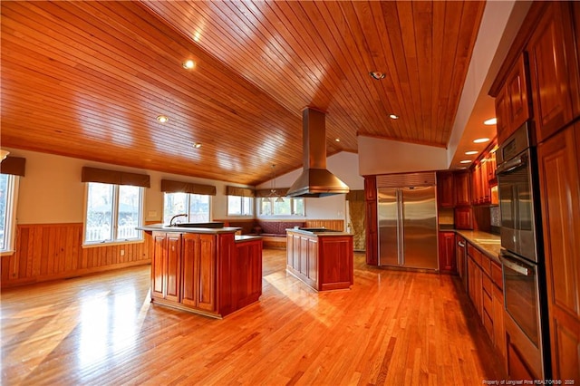 kitchen featuring lofted ceiling, light hardwood / wood-style flooring, appliances with stainless steel finishes, a center island, and island exhaust hood