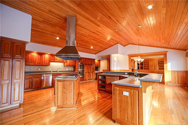 kitchen featuring stainless steel appliances, hanging light fixtures, a center island with sink, and island range hood