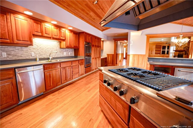 kitchen with decorative light fixtures, lofted ceiling, sink, light hardwood / wood-style floors, and stainless steel appliances