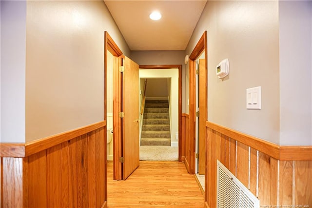 corridor featuring light hardwood / wood-style floors and wood walls