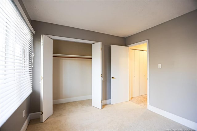 unfurnished bedroom with light carpet and a closet