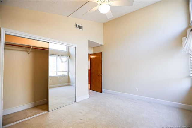 unfurnished bedroom featuring ceiling fan, high vaulted ceiling, light carpet, and a closet