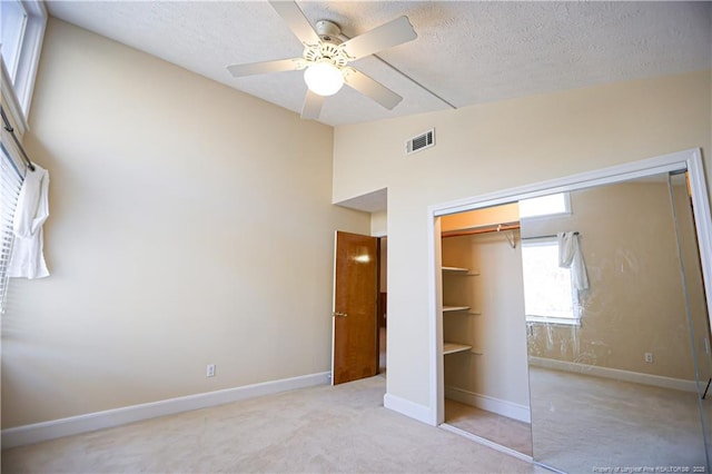 unfurnished bedroom featuring high vaulted ceiling, light carpet, a textured ceiling, a closet, and ceiling fan