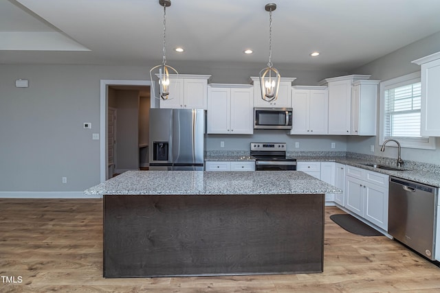 kitchen featuring stainless steel appliances, a kitchen island, sink, and decorative light fixtures