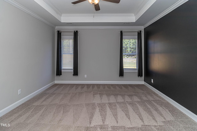 unfurnished room featuring ceiling fan, light colored carpet, ornamental molding, and a raised ceiling