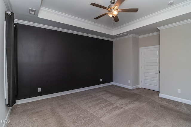 carpeted spare room with crown molding, a tray ceiling, and ceiling fan