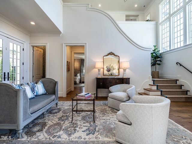 living area featuring a healthy amount of sunlight, a towering ceiling, stairway, and wood finished floors