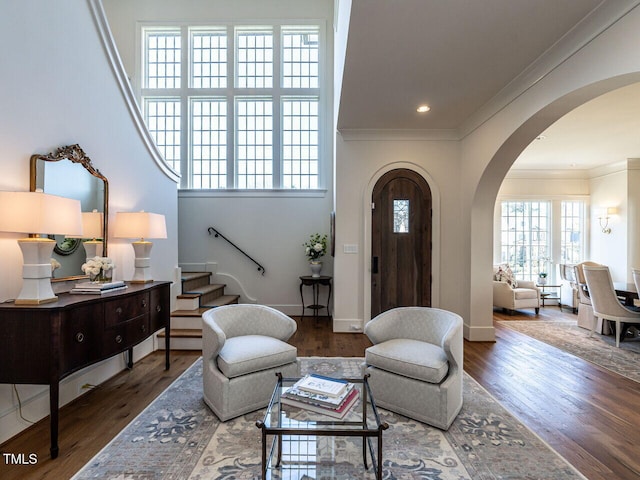 interior space with arched walkways, crown molding, stairway, and wood finished floors