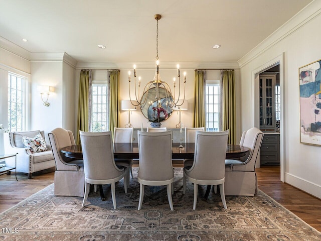 dining room featuring a chandelier, ornamental molding, wood finished floors, and baseboards