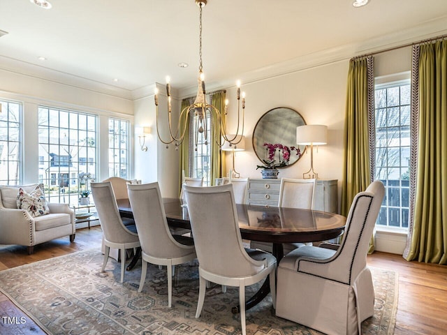 dining space with ornamental molding, a chandelier, and wood finished floors