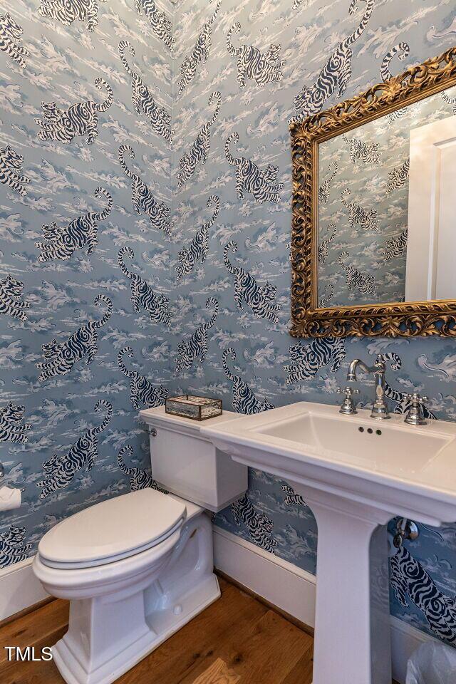 bathroom with wood finished floors, baseboards, toilet, and wallpapered walls